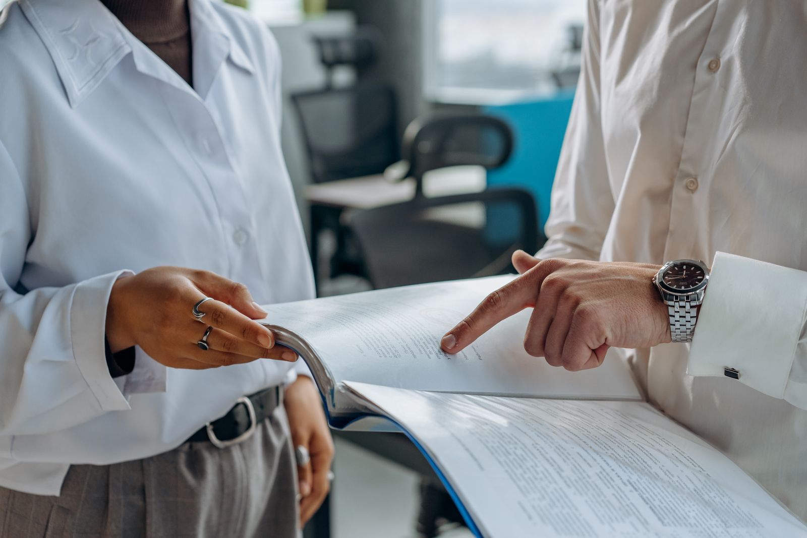 Two colleagues standing together reviewing a financial report